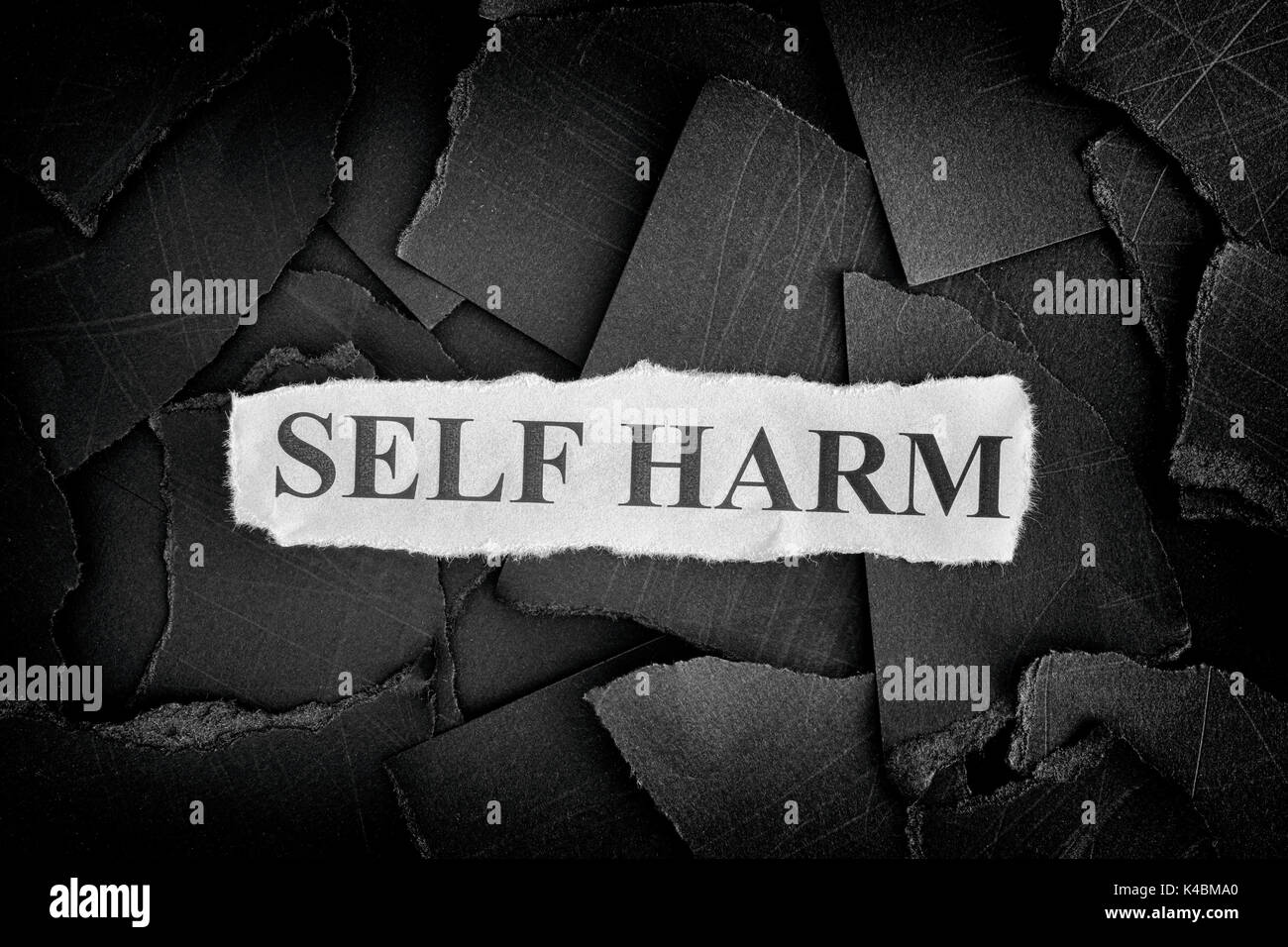 Self Harm. Torn pieces of black paper and words Self Harm. Concept Image. Black and White. Closeup. Stock Photo