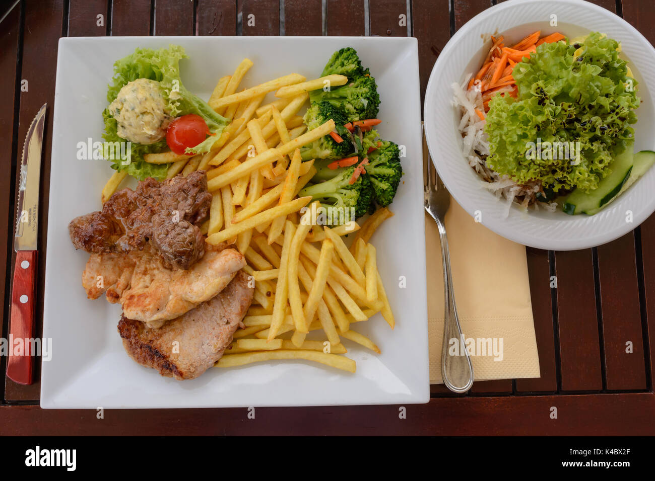 Rustic Meat Dish With French Fries And Salad On The Table Stock Photo