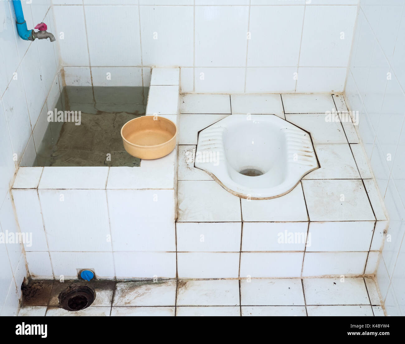 Dirty public toilet with the plastic water bowl in the small temple