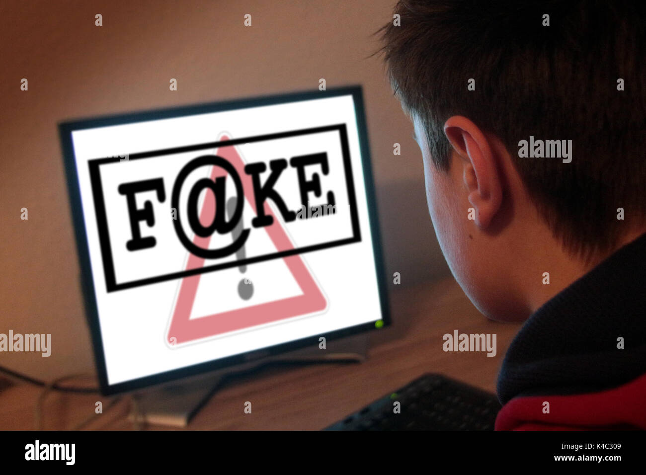 Young Man In Front Of A Computer With Words Fake News Stock Photo