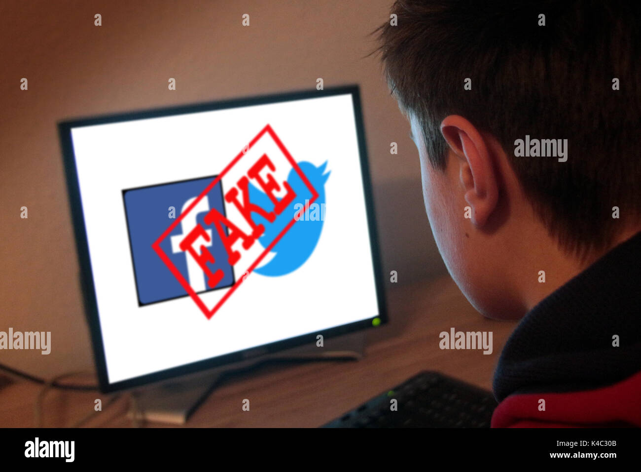 Young Man In Front Of A Computer With Words Fake News Stock Photo