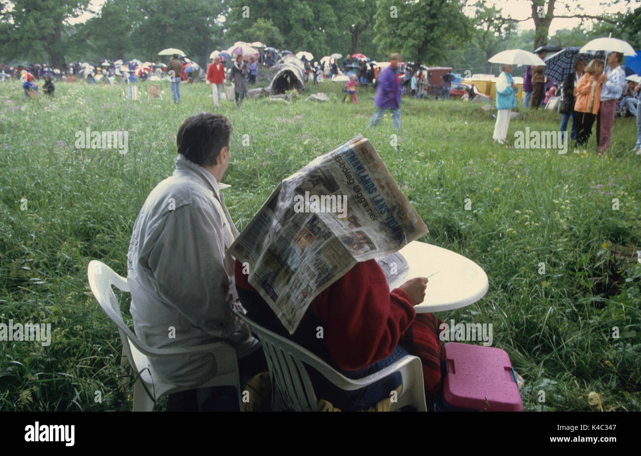 PEOPLE sneak under their umbrellas and newspaper during summer rain 2009 Stock Photo