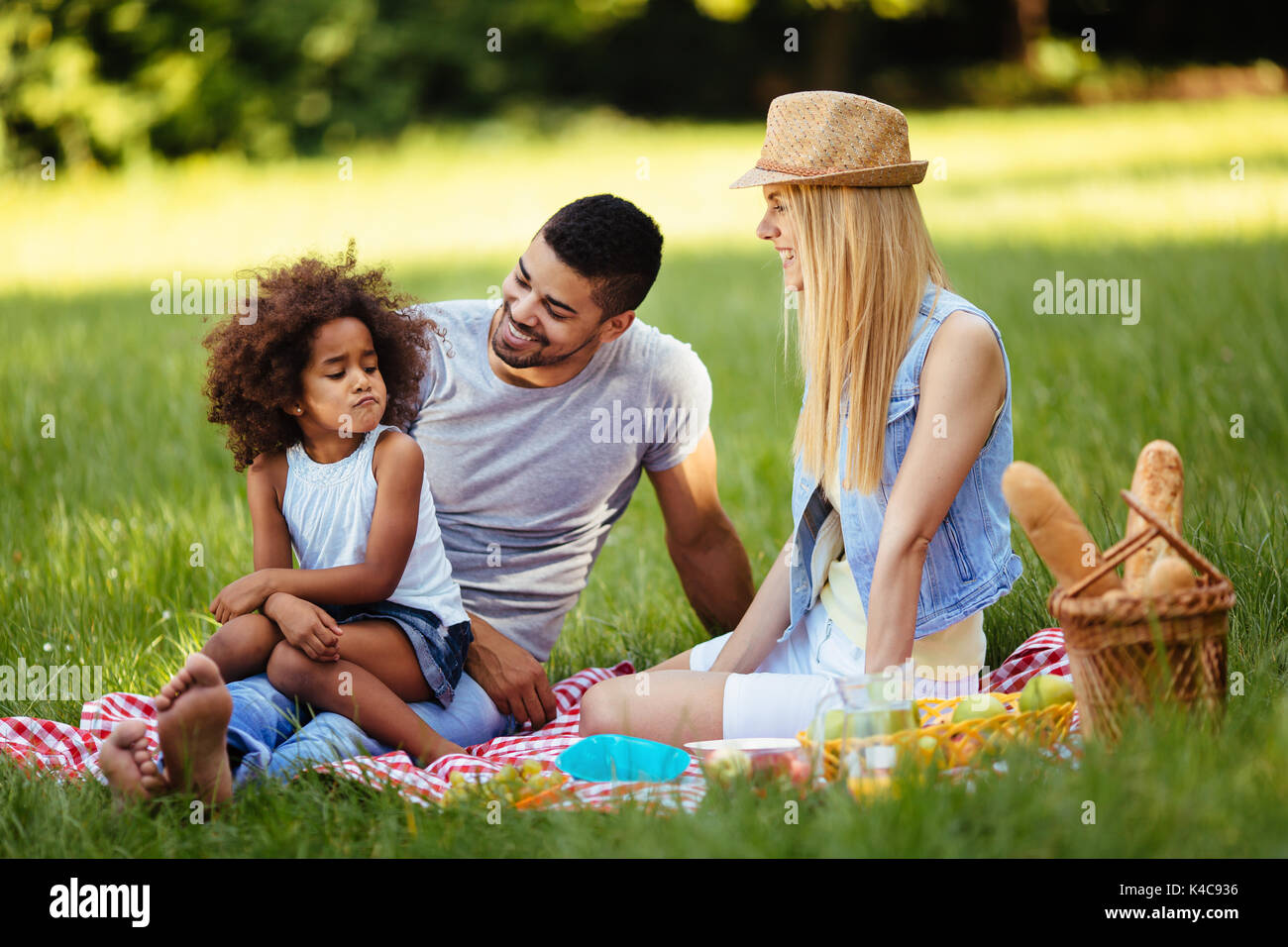 Offended little girl sitting with parents on picnic Stock Photo