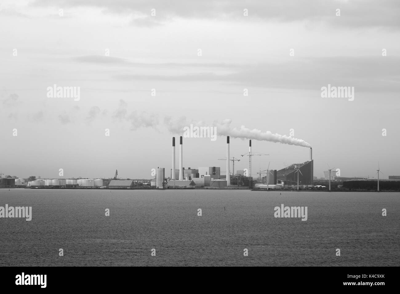 factory chimney emitting fumes into the atmosphere, close to the sea Stock Photo