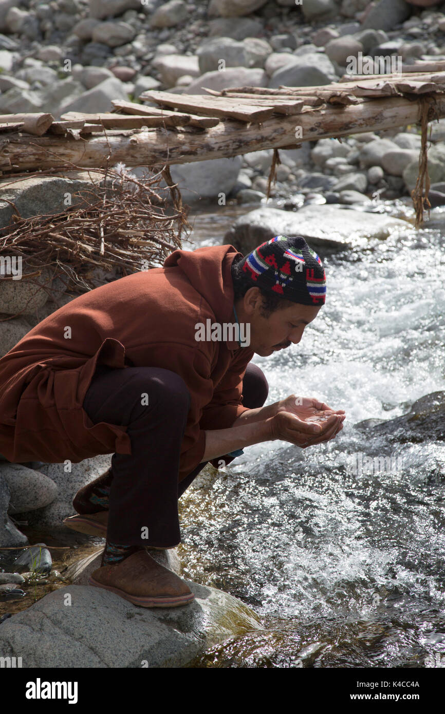 Berber man drinking from river, Setti Fatma market, Ourika valley, Morocco Stock Photo