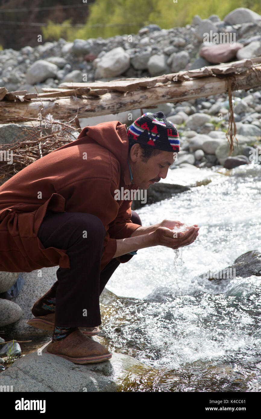 Berber man drinking from river, Setti Fatma market, Ourika valley, Morocco Stock Photo