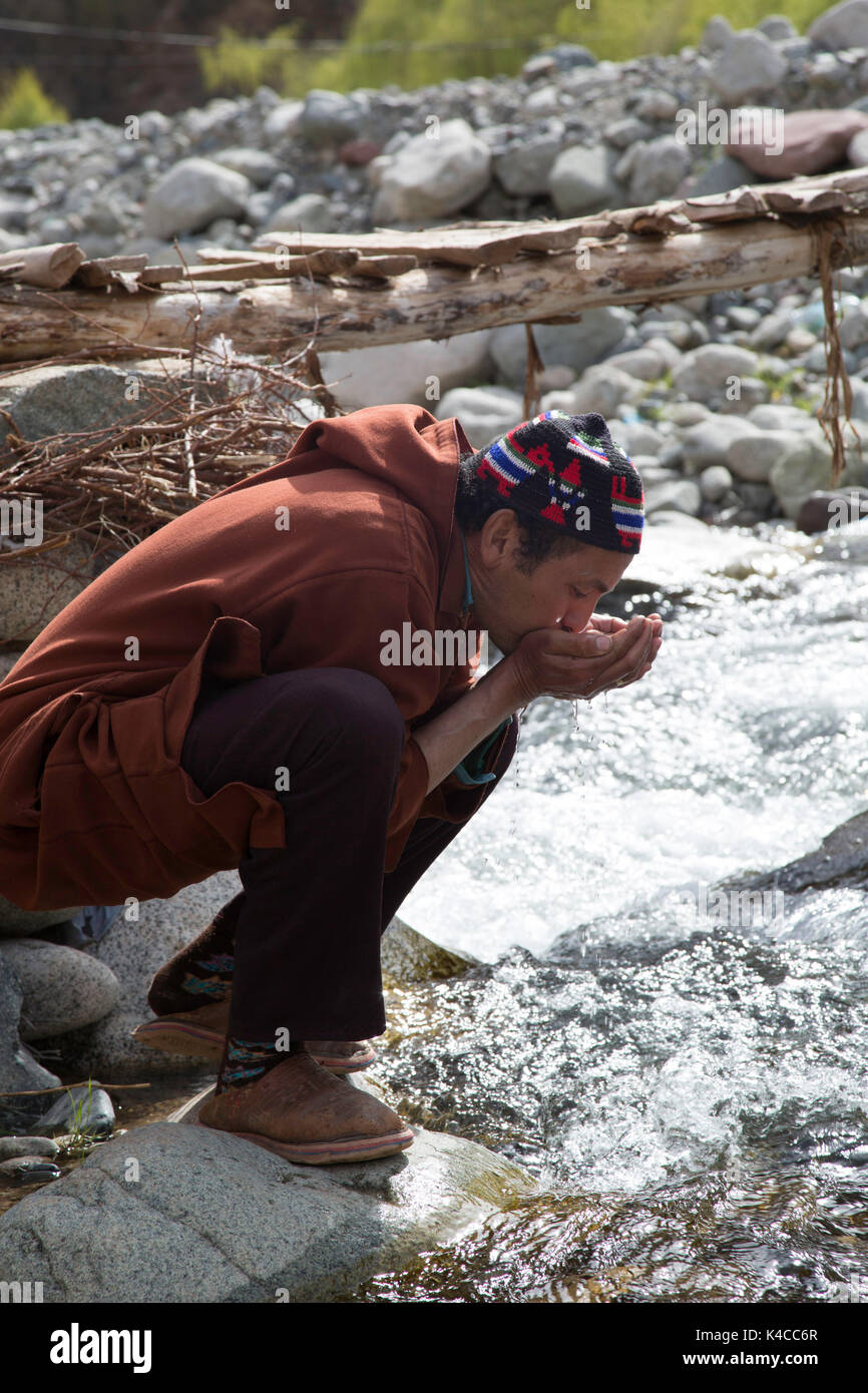 Berber man drinking from river, Setti Fatma market, Ourika valley, Morocco Stock Photo