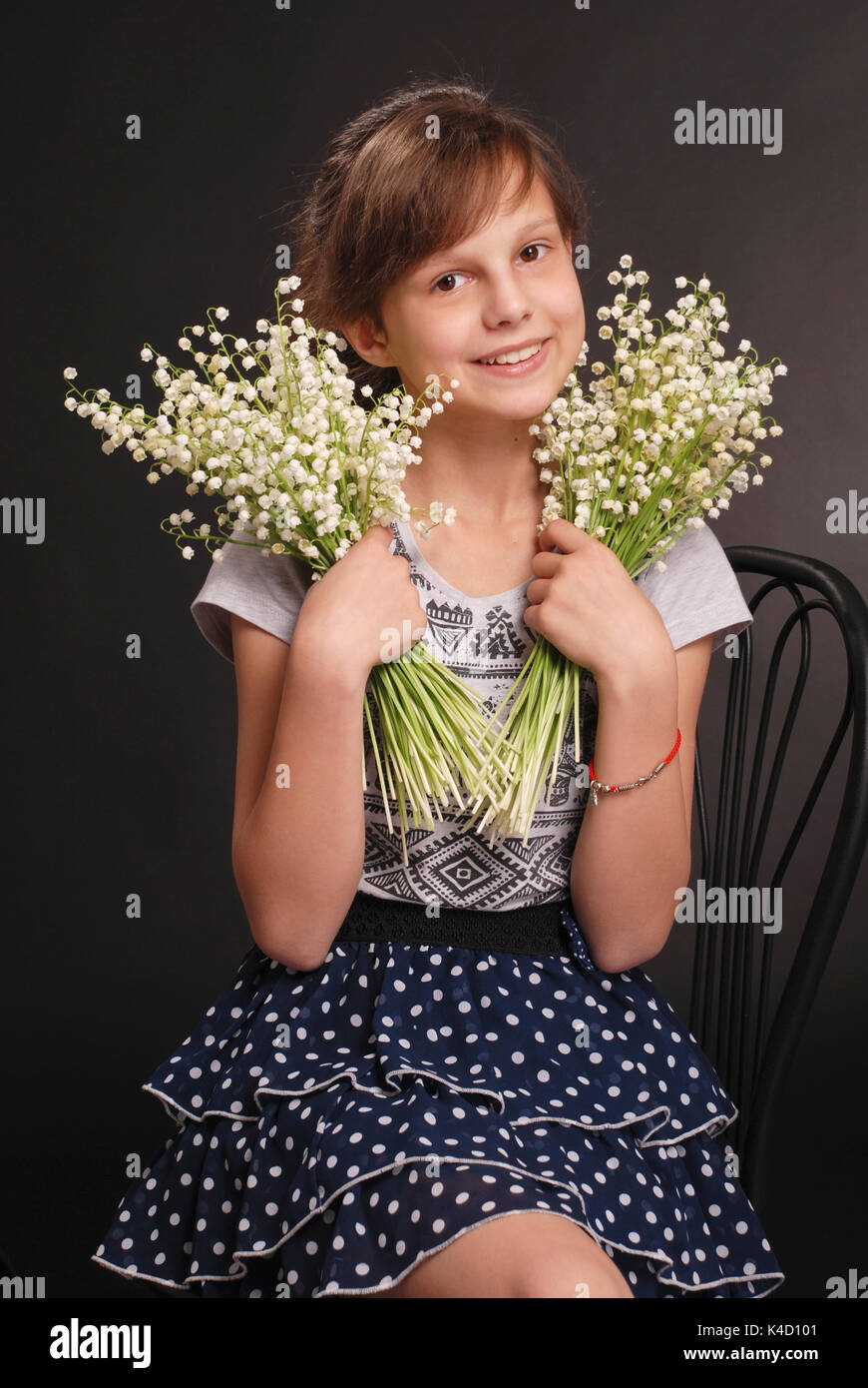 Portrait of adorable smiling girl sitting on a chair with a bouquet of ...
