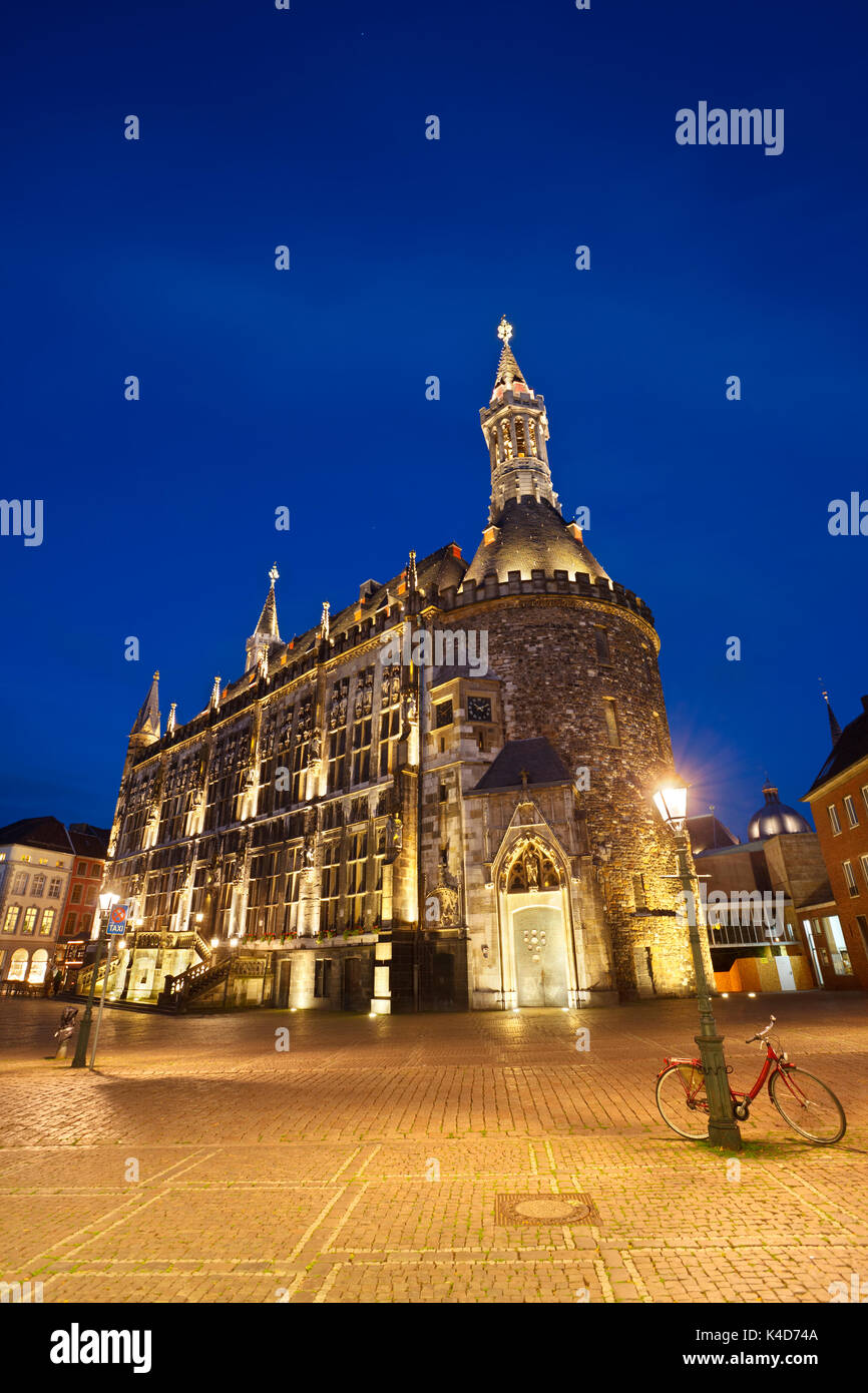 The town hall of Aachen, Germany with night blue sky and illumination. A lonely bike in the foreground. Stock Photo