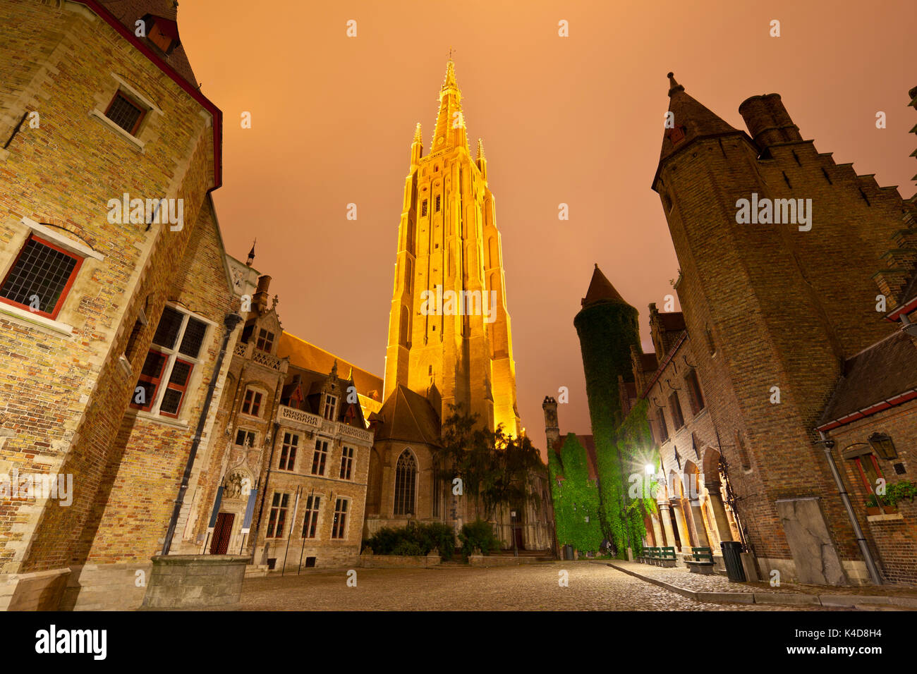 View to the illuminated tower of the Church Of Our Lady in Bruges at night with the Gruuthuse Museum buildings as foreground. Stock Photo