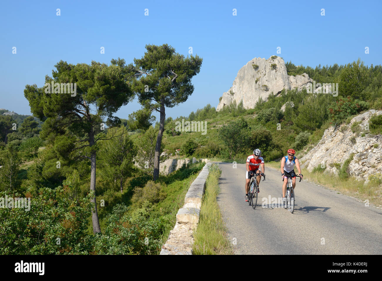 Two Cyclists Cycling on Country Road near Les Baux-de-Provence in the Alpilles Hills Provence France Stock Photo