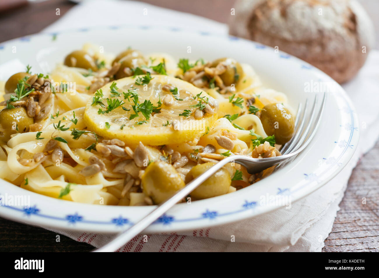 Sicilian tagliatelle pasta with lemon, garlic and olives, garnished with sunflower seeds. Stock Photo