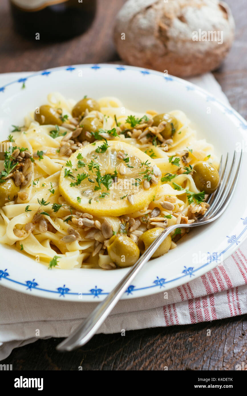 Sicilian tagliatelle pasta with lemon, garlic and olives, garnished with sunflower seeds. Stock Photo