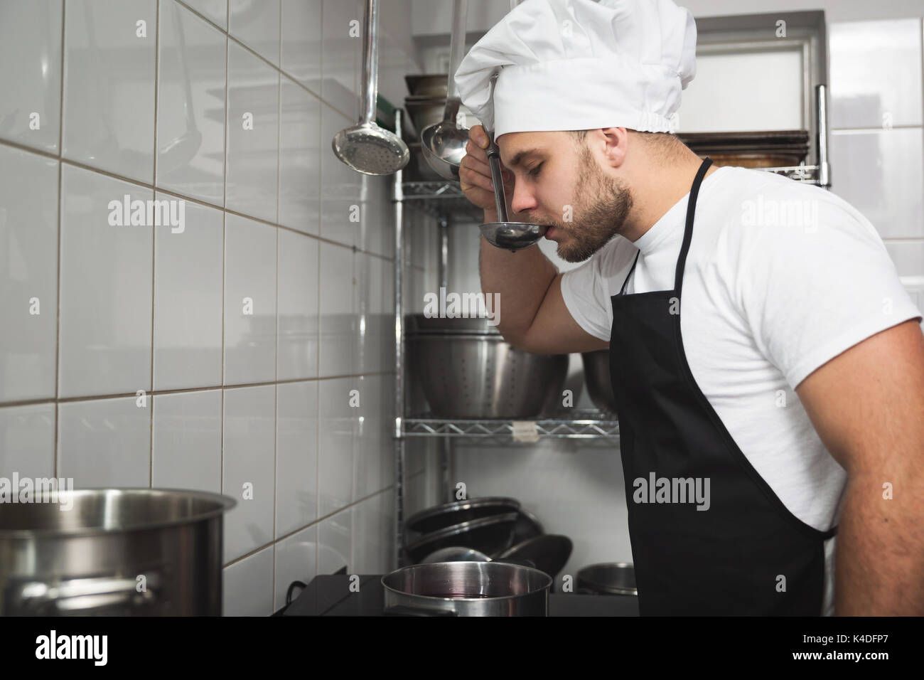 Side portrait of chef cooking soup tasting it Stock Photo - Alamy