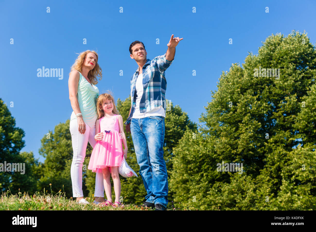 Young family on field, Dad pointing at something Stock Photo