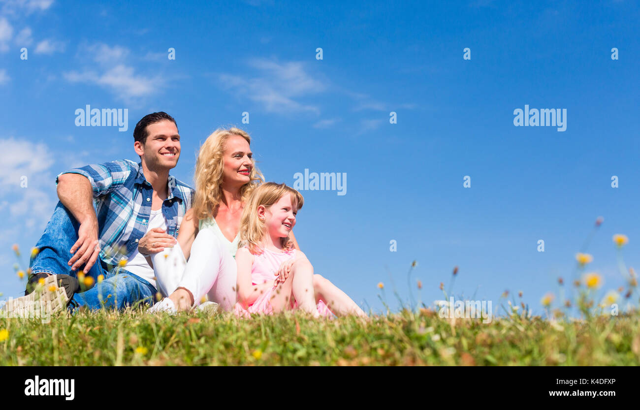 Family sitting in green grass on meadow Stock Photo