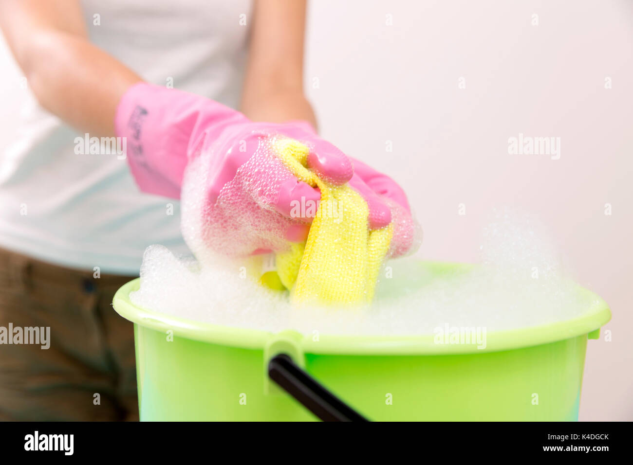 Close-up of cleaner woman hand squeezing cloth in bucket filled with soap Stock Photo