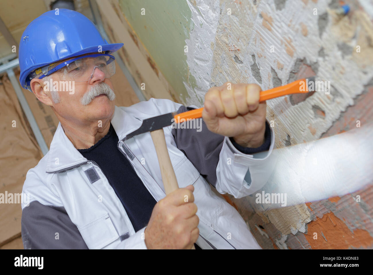 senior construction worker with a chisel and hammer Stock Photo - Alamy
