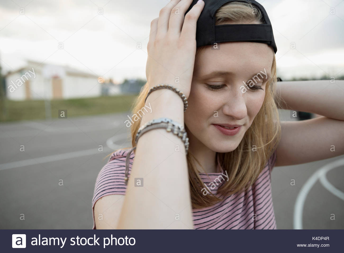 Teenage girl wearing backward baseball cap on outdoor basketball court Stock Photo