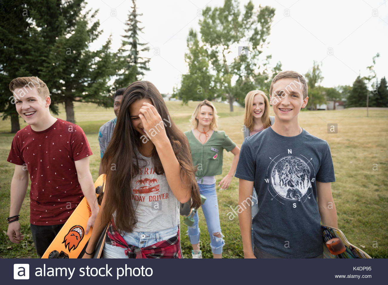 Teenagers walking with skateboards in park grass Stock Photo Alamy