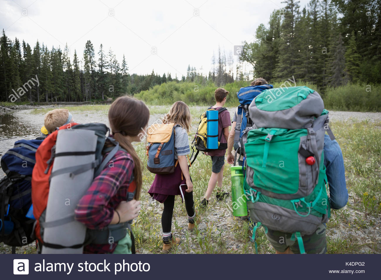 Teenage outdoor school students with backpacks hiking in woods Stock Photo