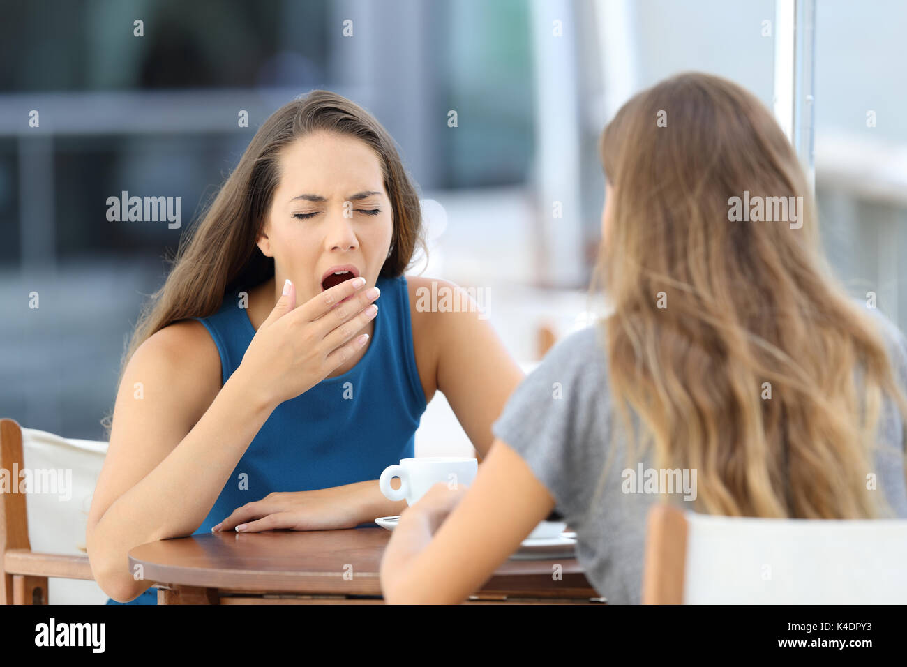 Bored friend having a conversation sitting in a coffee shop outdoors Stock Photo