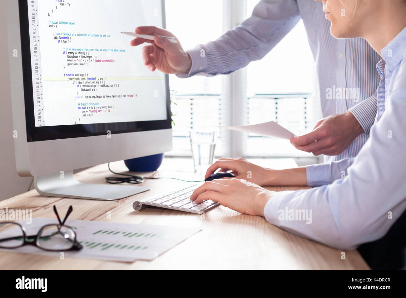 Team of web app developers coding website source code and debugging on computer screen before deployment Stock Photo