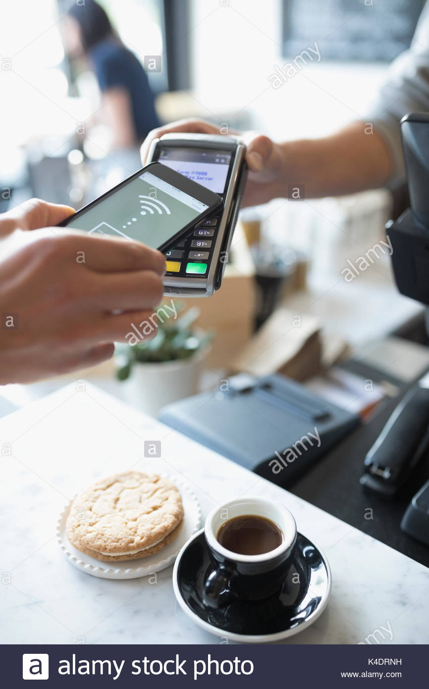 Customer paying with smart phone contactless payment at cafe Stock Photo