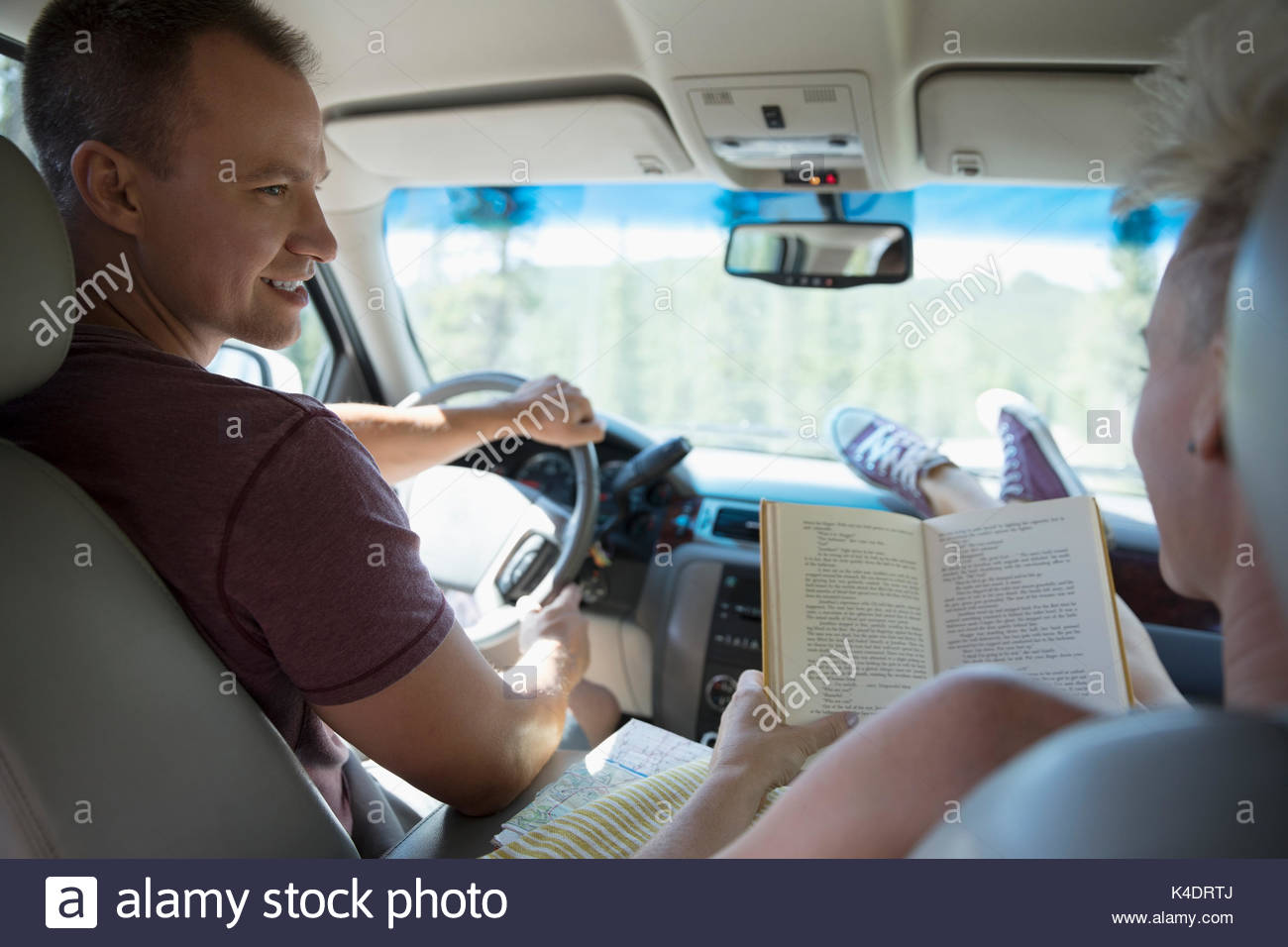 Couple driving and reading in car, enjoying road trip Stock Photo