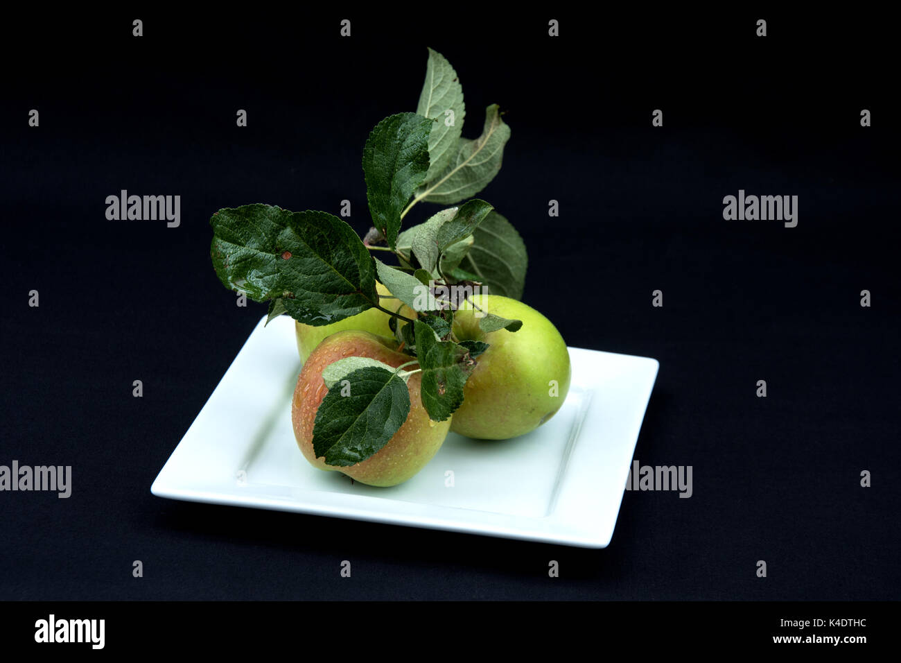 Three apples on a white plate. Stock Photo
