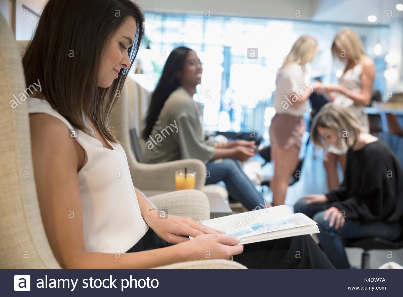 Woman reading magazine and getting pedicure in nail salon Stock Photo