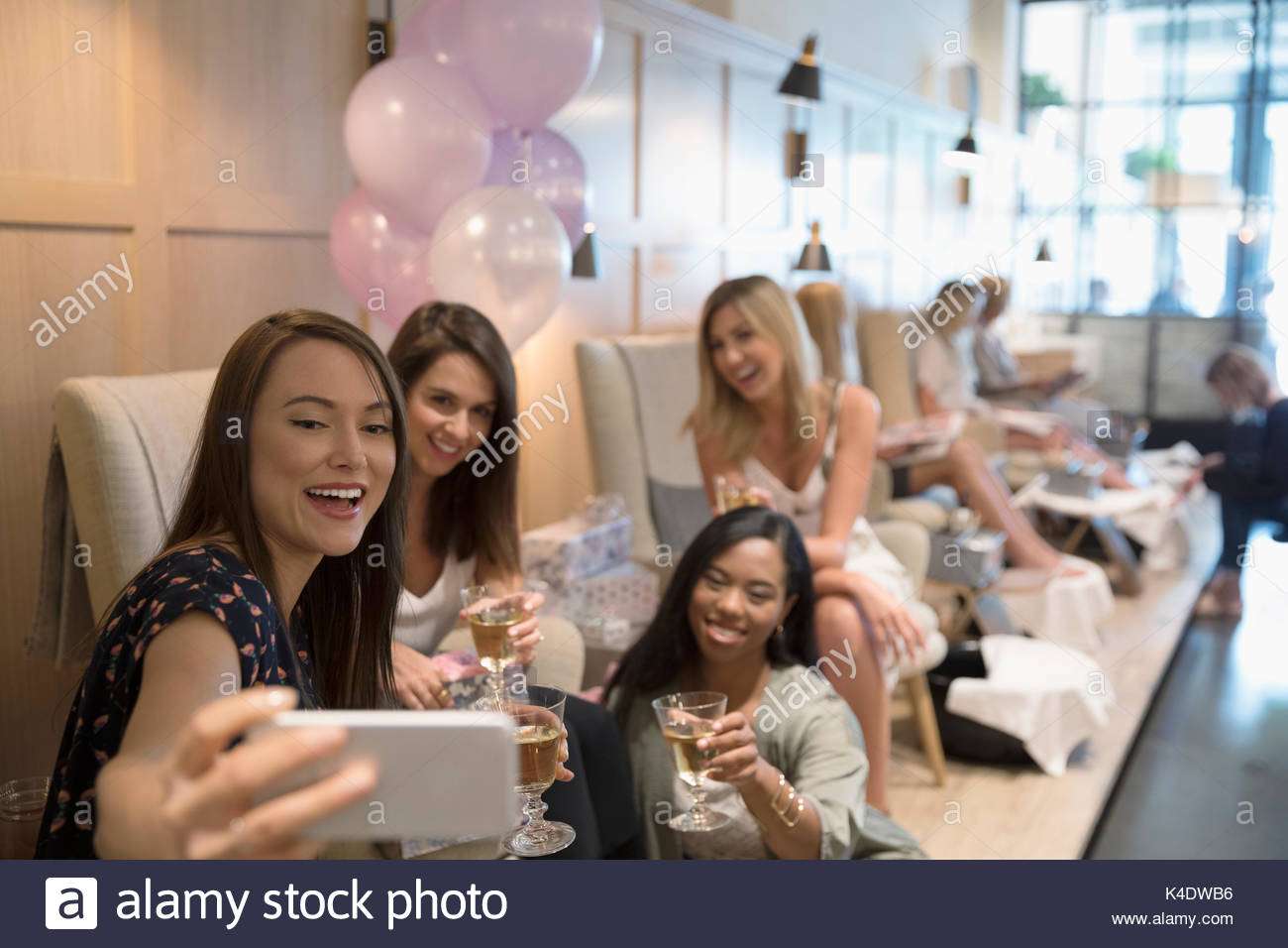 Smiling bridesmaid friends and bride-to-be taking selfie in nail salon Stock Photo