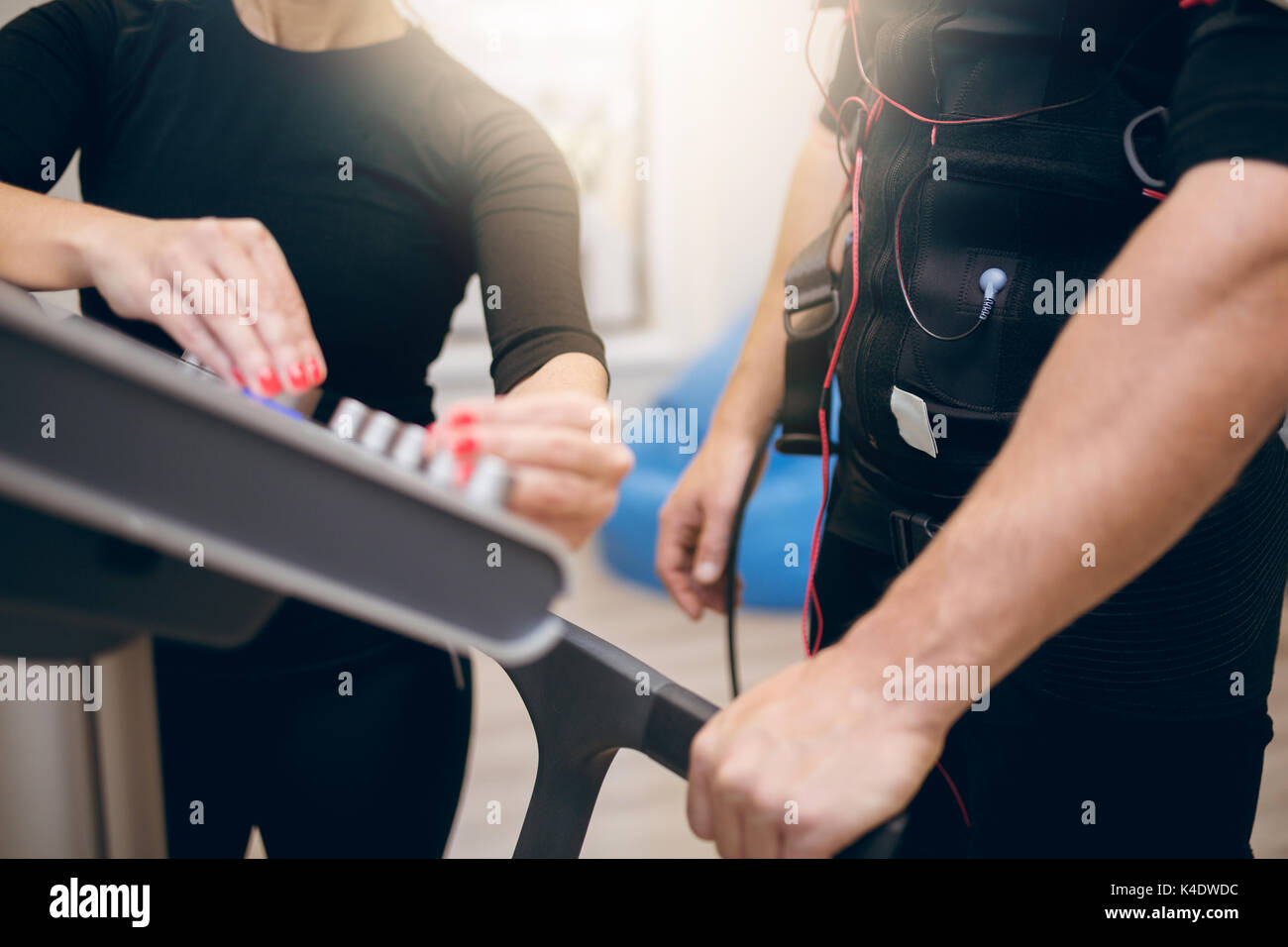 Close up cropped portrait of sportsman and trainer hands on ems device Stock Photo