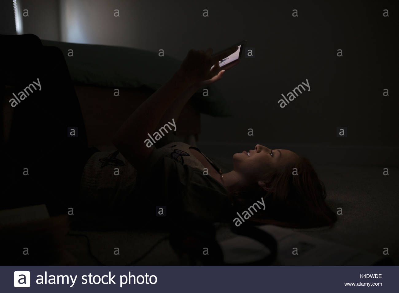 Teenage girl using digital tablet upsidedown on dark bedroom floor Stock Photo Alamy