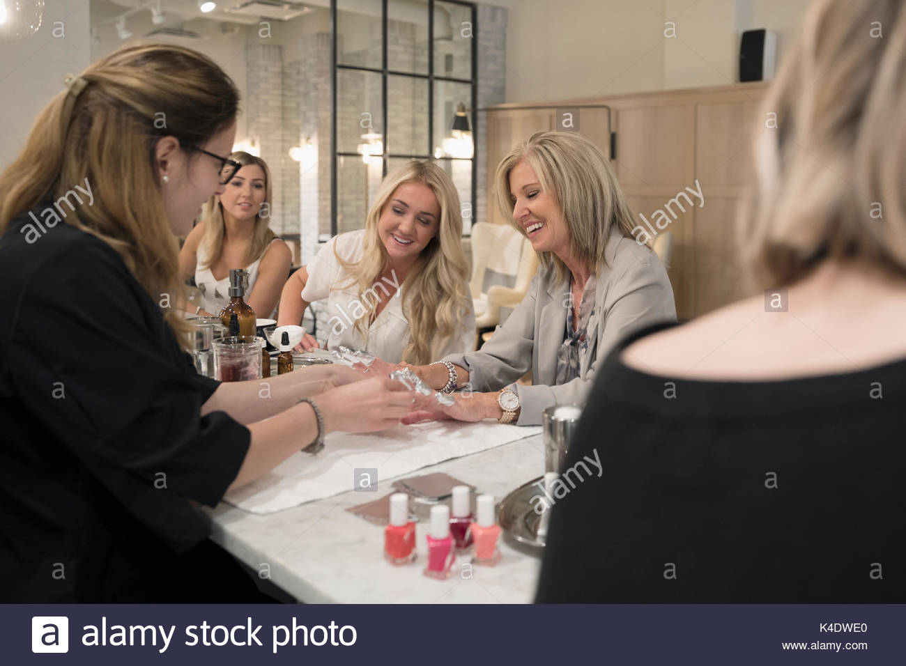 Female nail technician giving manicure to mother and adult daughters in nail salon Stock Photo