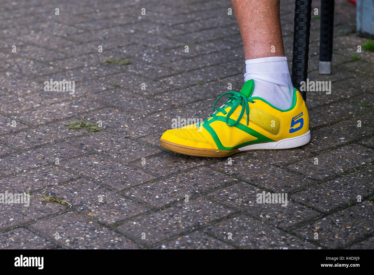 A left foot wearing a brightly coloured yellow Umbro trainer. Stock Photo