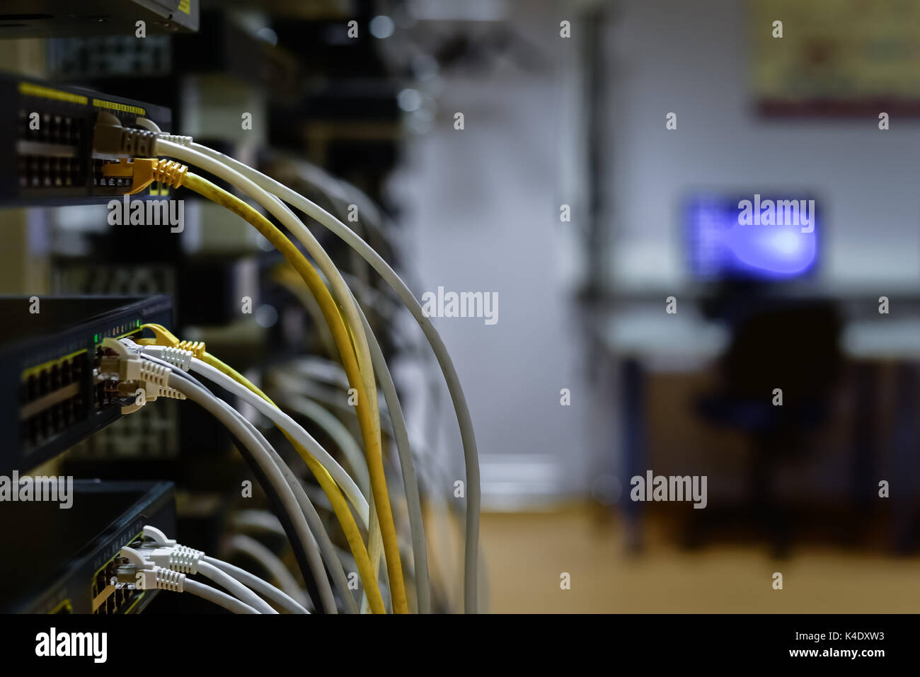 RJ45 cables plugged into switches in rack with work space on background Stock Photo