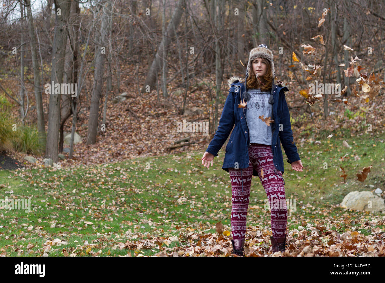 Autumn leaves falling on happy young woman in forest Stock Photo