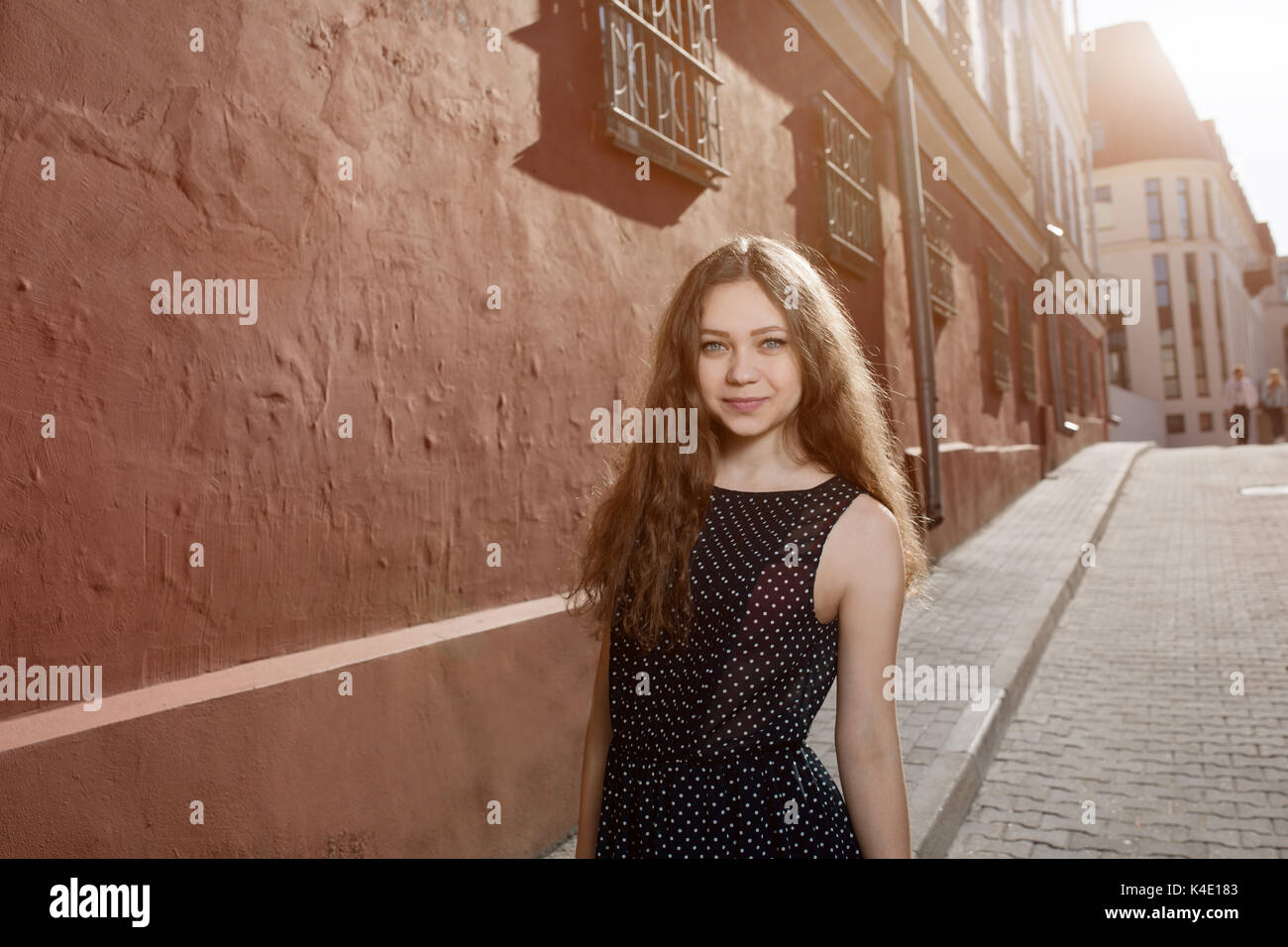 Beautiful brunette young woman wearing dress and walking on the street ...
