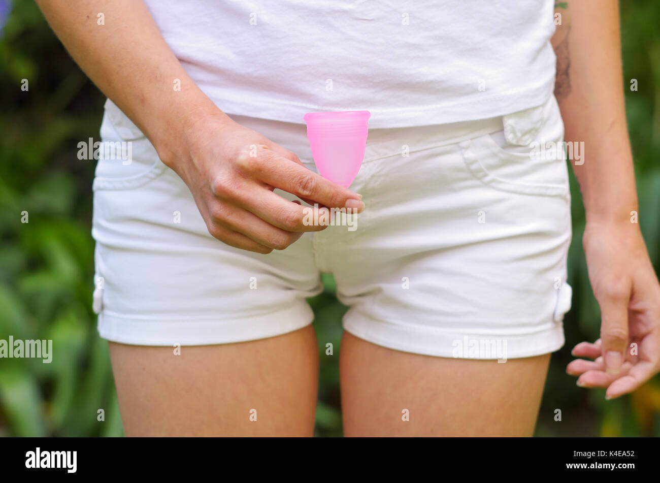Close up view of young woman holding a menstrual cup in front of her private parts. Gynecology concept Stock Photo