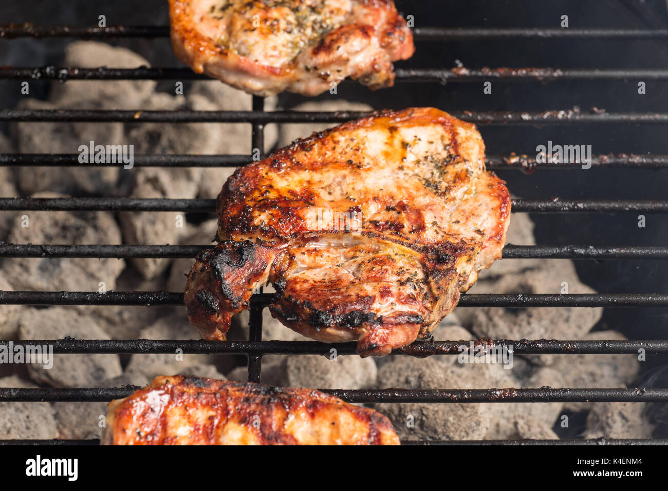 Seasoned pork chops and lamb steak cooking on the charcoal bbq grill