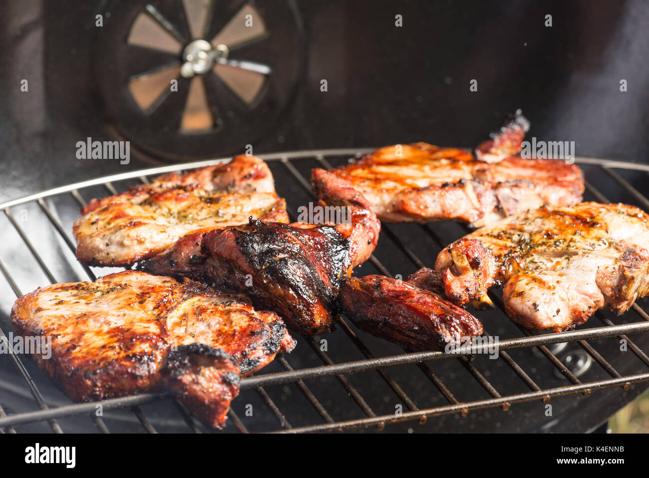 Seasoned pork chops and lamb steak cooking on the charcoal bbq grill