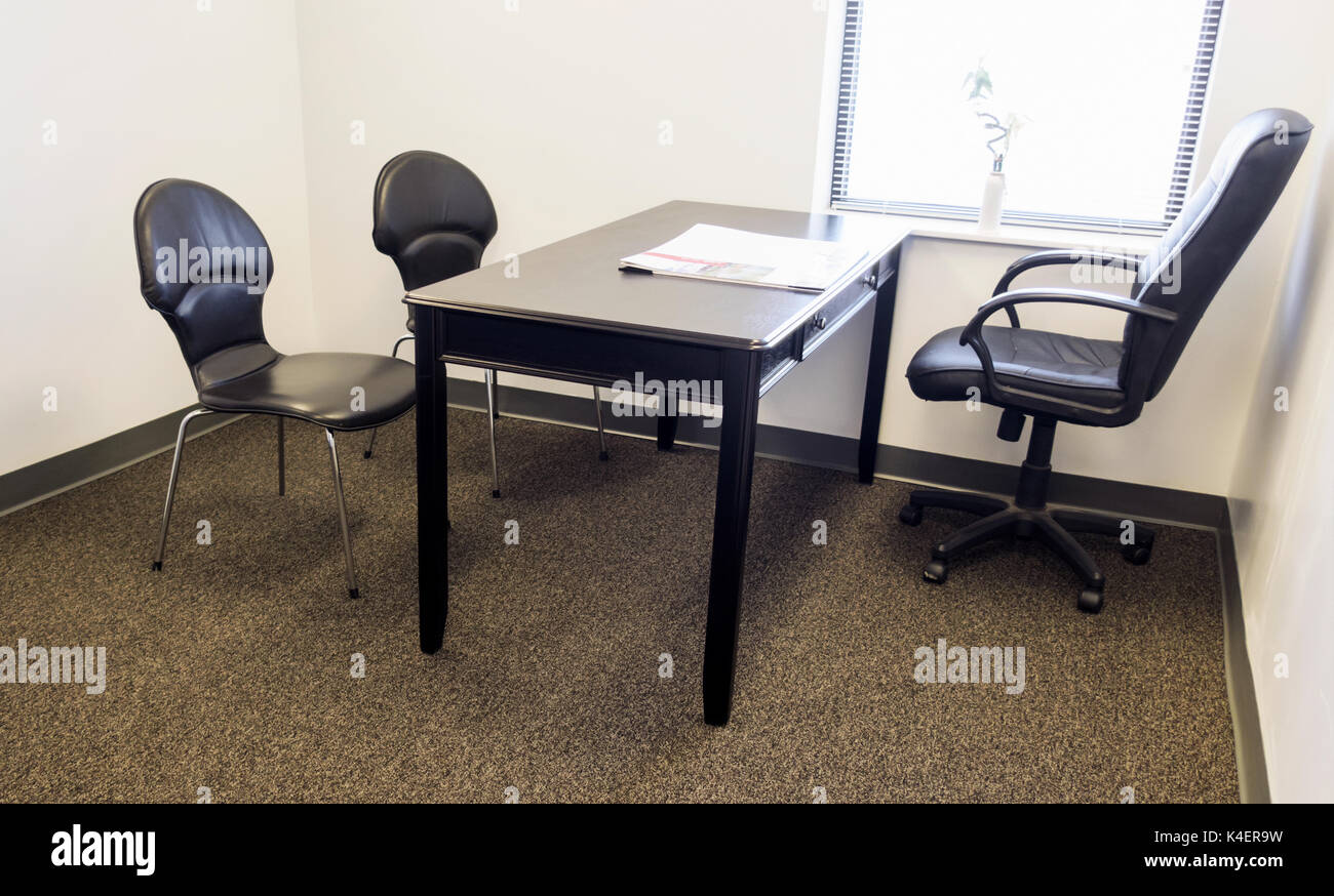 A basic office space with two plastic chairs facing a leather office