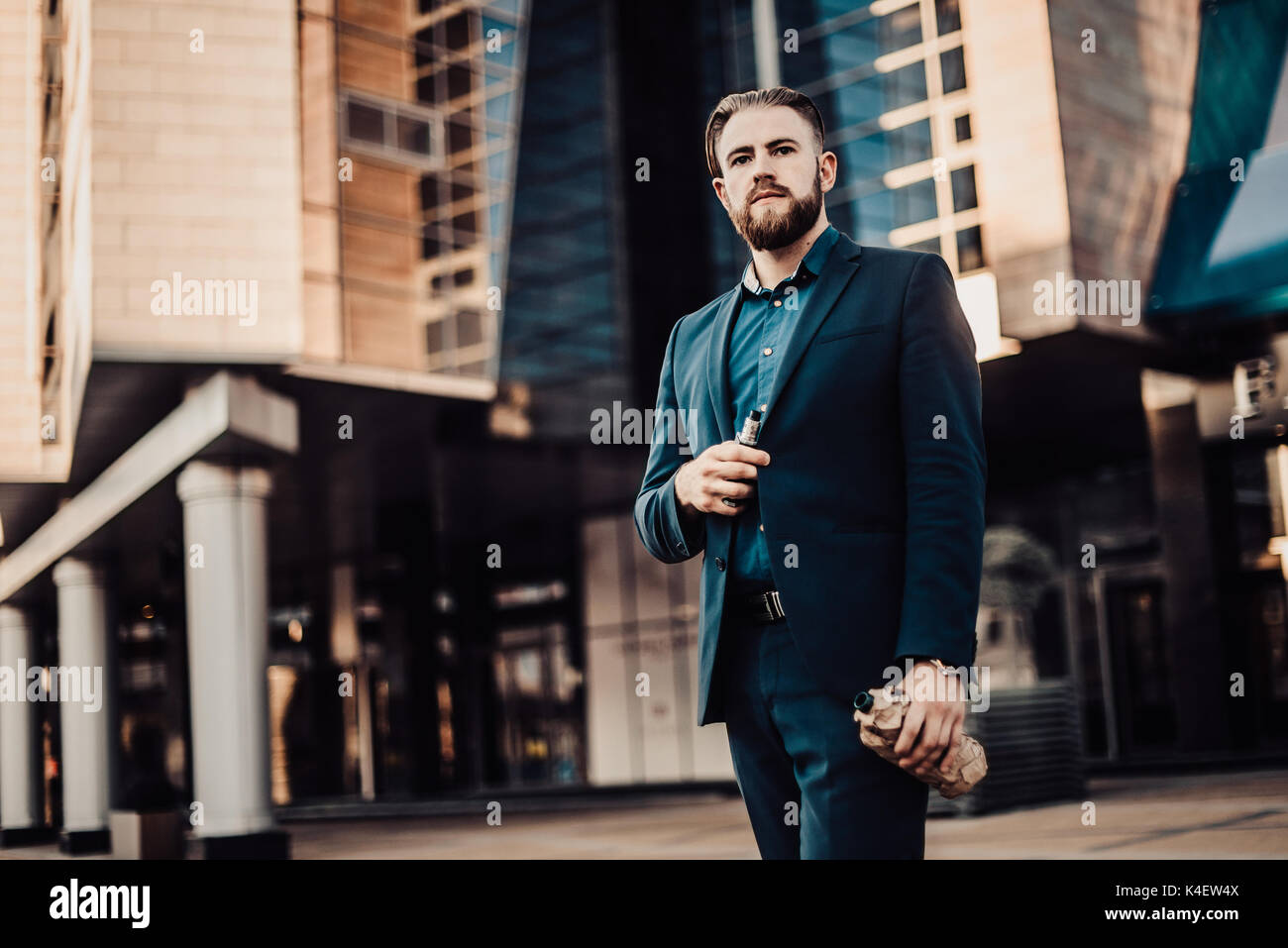 bearded man in a suit in the urban landscape with a bottle of something Stock Photo
