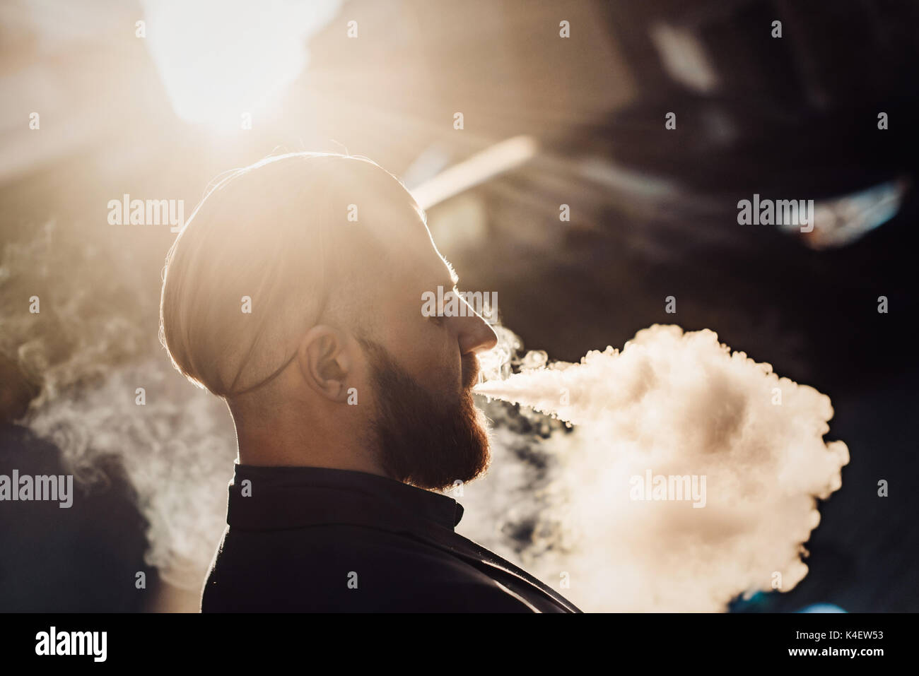 bearded man in a suit in the city vaping Stock Photo