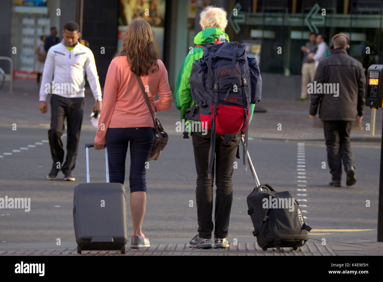 Glasgow street scene American tourists crossing toad at traffic lights with trolley cases and rucksack Stock Photo