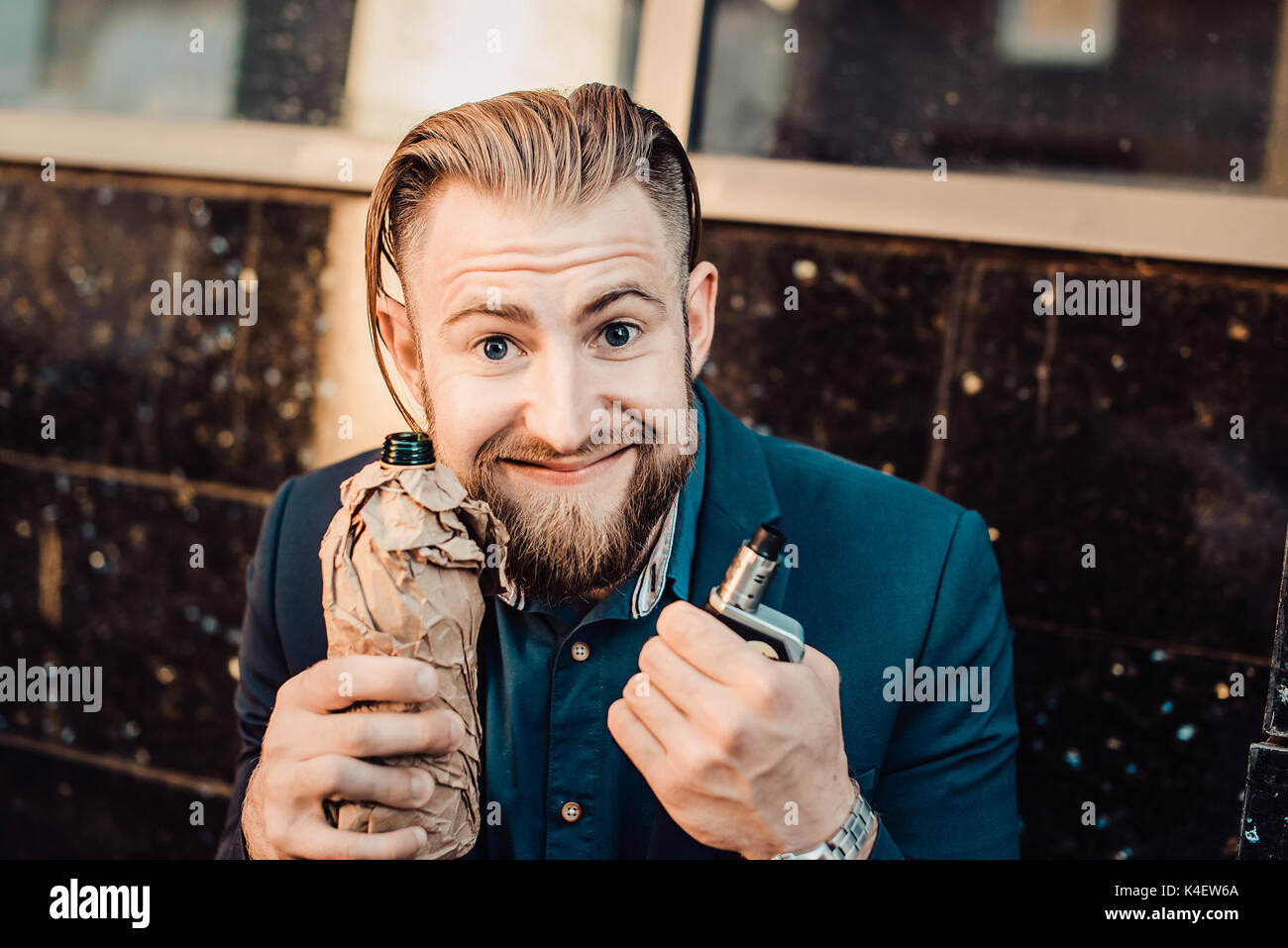 bearded man in a suit in the urban landscape with a bottle of something Stock Photo