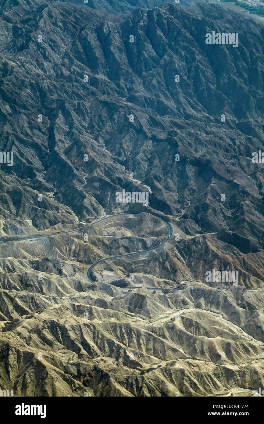 Pan-American Highway winds it's way through eroded hills in the desert south of Ica, Peru, South America - aerial Stock Photo