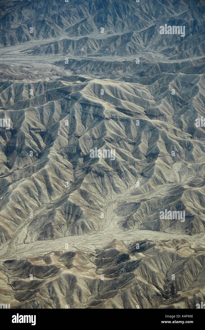 Eroded hills and dry river beds in the desert south of Ica, Peru, South America - aerial Stock Photo