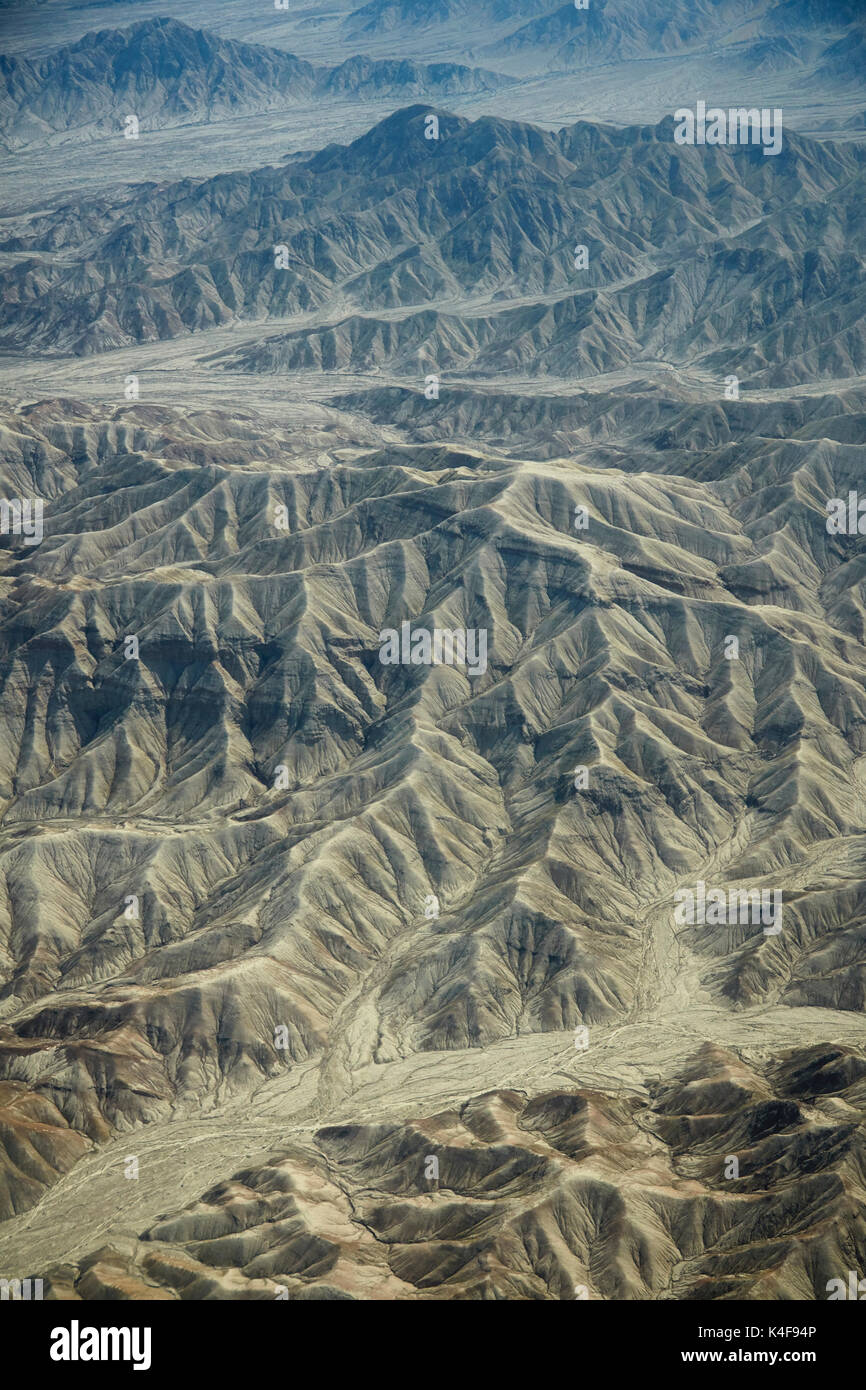 Eroded hills and dry river beds in the desert south of Ica, Peru, South America - aerial Stock Photo